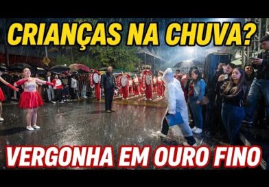 VERGONHA DE OURO FINO. Crianças desfilam na chuva enquanto AUTORIDADES assistem de cobertura
